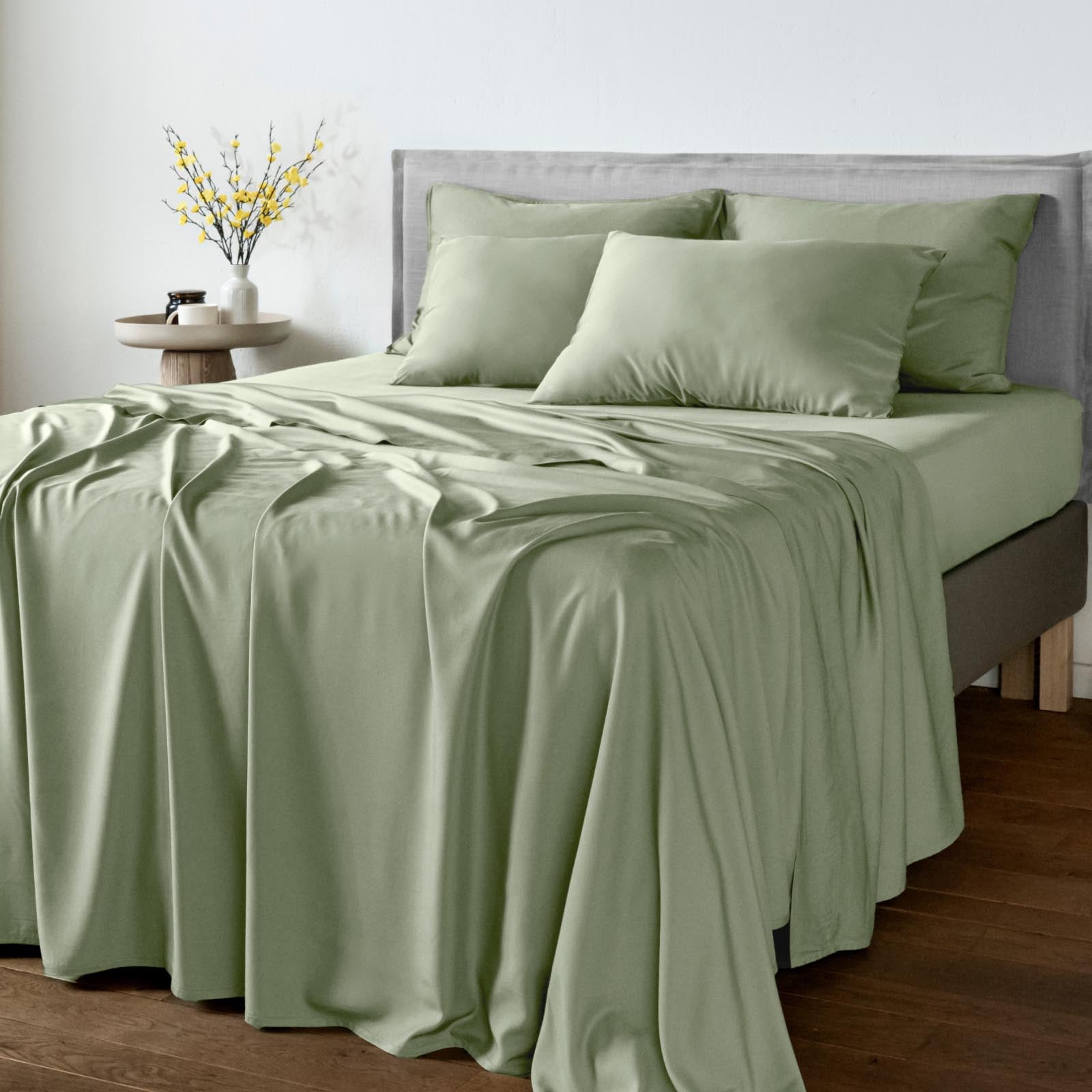 A bed dressed in Bambaw Cozy sage bamboo flat sheet with matching fitted sheet and pillowcases
