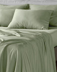 Light sage green bamboo bed sheets and matching pillowcases on a bed, shown in a clean, styled bedroom setting.