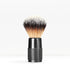 Shaving brush with a knurled black handle and dense light to dark bristles against a white background